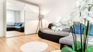 A modern living room with a sofa, a round rug, a floor lamp, and white orchids. - Gartenferienwohnung Arlberg (Bludenz)
