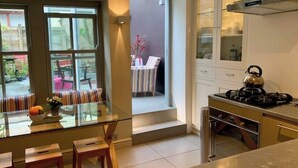 A modern kitchen with a glass dining table, a gas stove, and a view of the outdoor seating area.