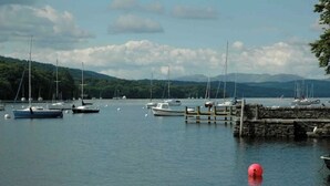 A marina with boats docked, a wooden pier, and a mountainous backdrop.