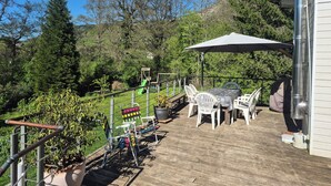 A wooden deck with outdoor furniture, a slide, and a metal railing. - Your stay in the Alps between lakes and mountains. (Saint-Théoffrey)