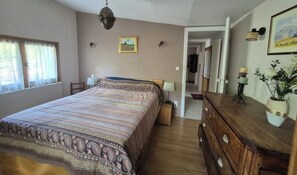 A bedroom with a bed, dresser, and a hallway leading to another room.