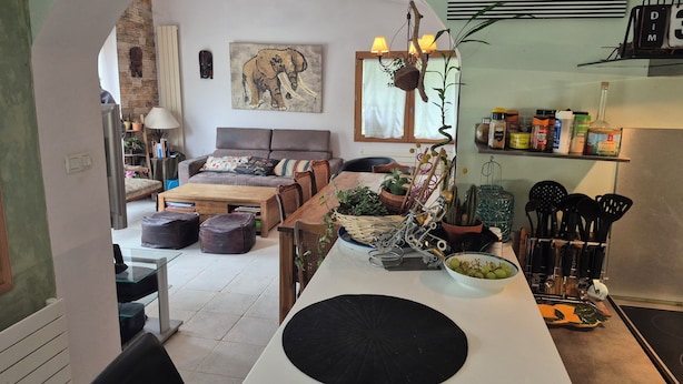 A cozy living room with a sofa, coffee table, and a dining area with a black circular table. - Your stay in the Alps between lakes and mountains. (Saint-Théoffrey)