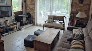 A living room with a stone wall, a fireplace, a sofa, a coffee table, and a television. - Your stay in the Alps between lakes and mountains. (Saint-Théoffrey)