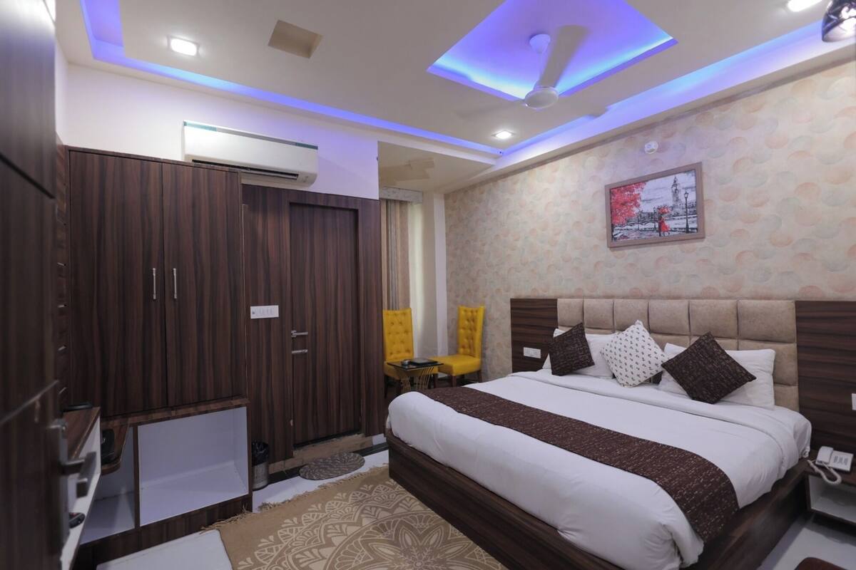 A hotel room with a large bed, a wardrobe, a desk, and a ceiling light.