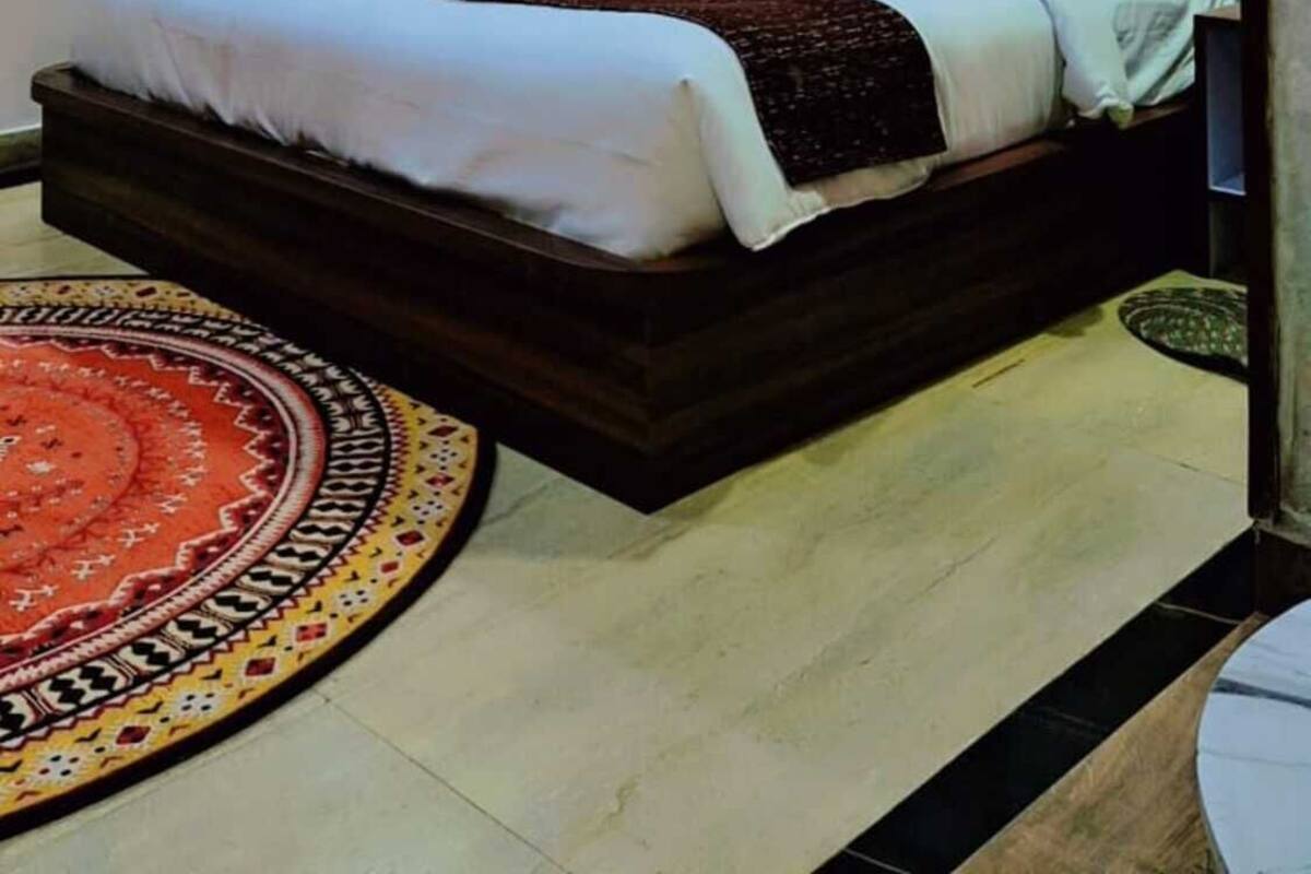 A bedroom with a bed, a ceiling fan, a framed picture on the wall, and a patterned rug.
