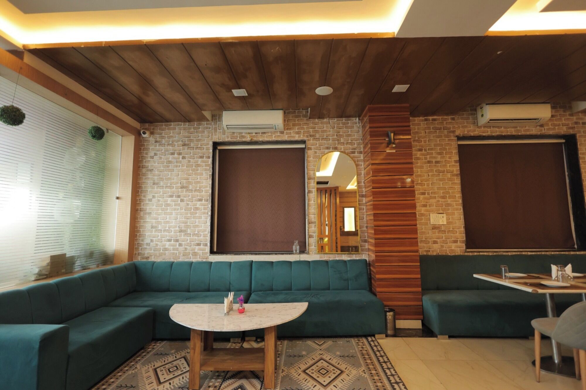 A modern living room with a green sofa, a small round table, and a brick wall.