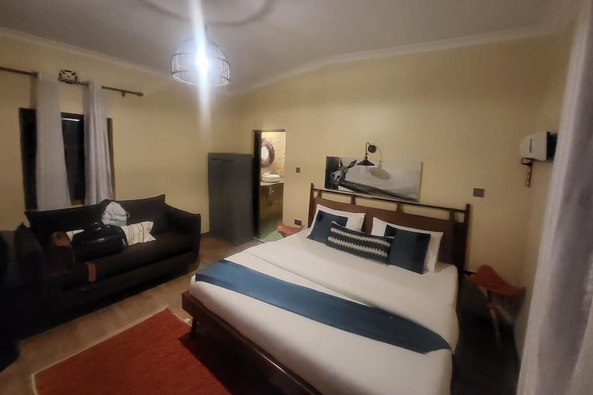 A hotel room with a bed, a sofa, a desk, and a mirror.