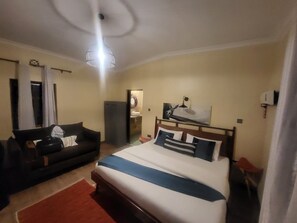 Una habitación de hotel con cama, sofá, escritorio y espejo.