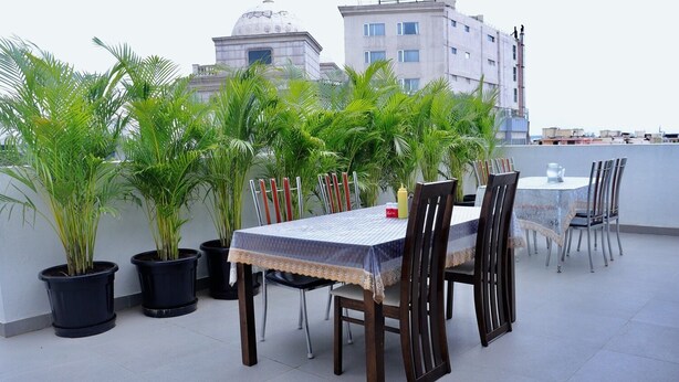 A rooftop terrace with a dining table and chairs, surrounded by potted plants. - Sweet Crystal Homes (Bengaluru)