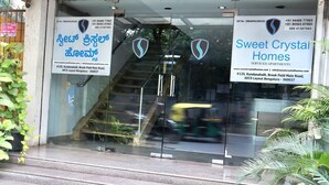 The entrance to Sweet Crystal Homes, featuring a glass door with a logo, contact information, and address. - Sweet Crystal Homes (Bengaluru)