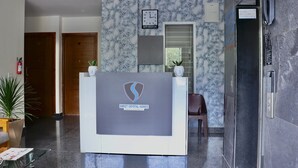 A reception desk with a logo, a clock, and a fire extinguisher on the wall. - Sweet Crystal Homes (Bengaluru)