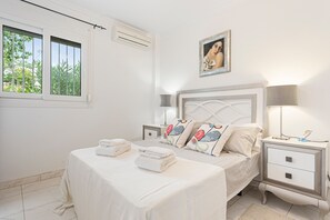 A bedroom with a bed, two bedside tables, a nightstand, a wall-mounted lamp, a framed picture, and a window with curtains. - Holiday Home 'Villa Eden' with Mountain View, Wi-Fi and Air Conditioning (Alcaucín)