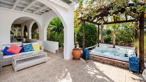 A covered outdoor seating area with a sofa, a hot tub, and a pergola with vines. - Holiday Home 'Villa Eden' with Mountain View, Wi-Fi and Air Conditioning (Alcaucín)