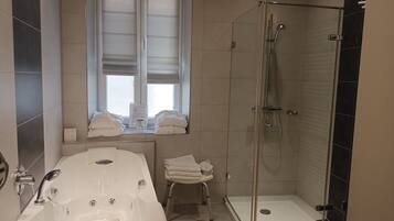 A modern bathroom with a bathtub, a shower, and a window.