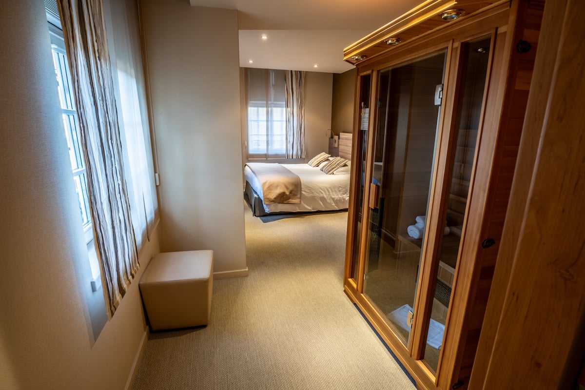 A hotel room with a large bed, a wardrobe, and a seating area.