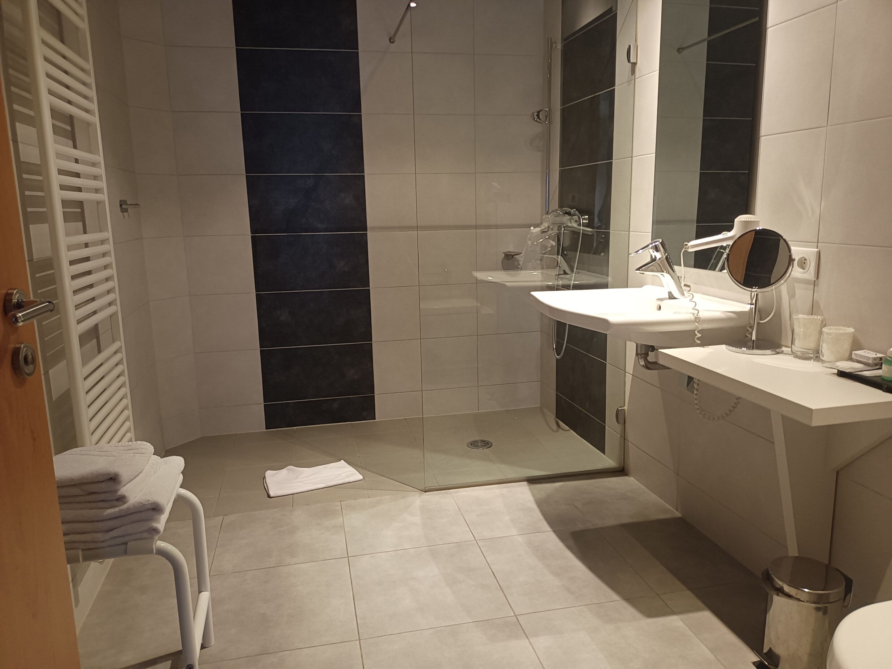 Un baño moderno con ducha, lavamanos y espejo.