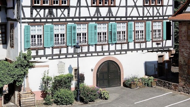 A traditional half-timbered building with a tiled roof, multiple windows, and a central arched entrance. - L'Ecrevisse (Wissembourg)