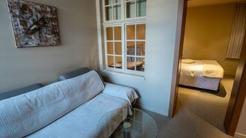 Ein modernes Zimmer mit einer Couch, einem Glastisch, einem Fenster und einem Bett.