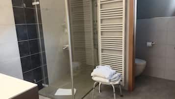 Une salle de bain moderne avec une douche à parois de verre, un porte-serviettes blanc et des toilettes.