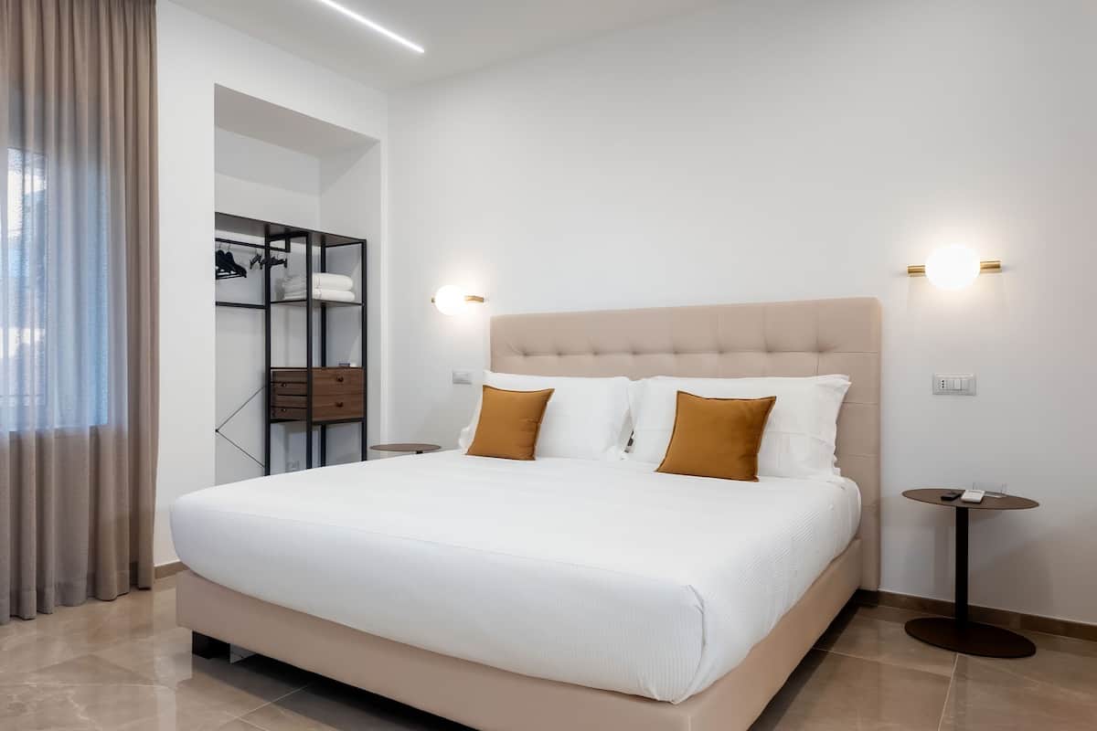 Una habitación de hotel moderna con una cama grande, un armario y una mesa redonda.