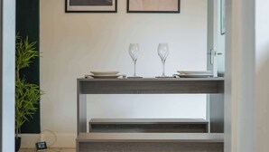 A modern, minimalist dining area with a wooden console table and two wine glasses.