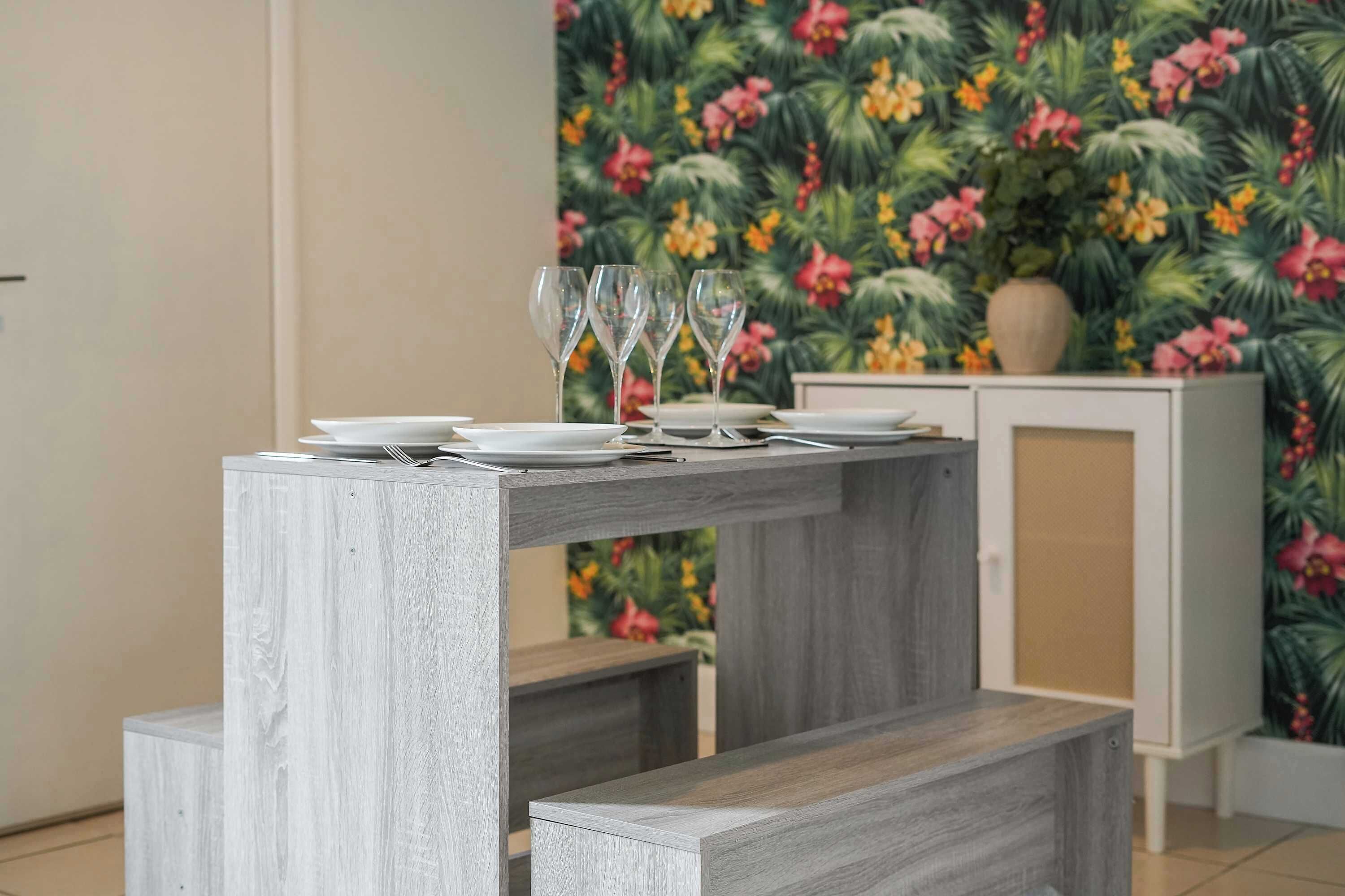 A dining area with a wooden table set for four, glasses, and plates.