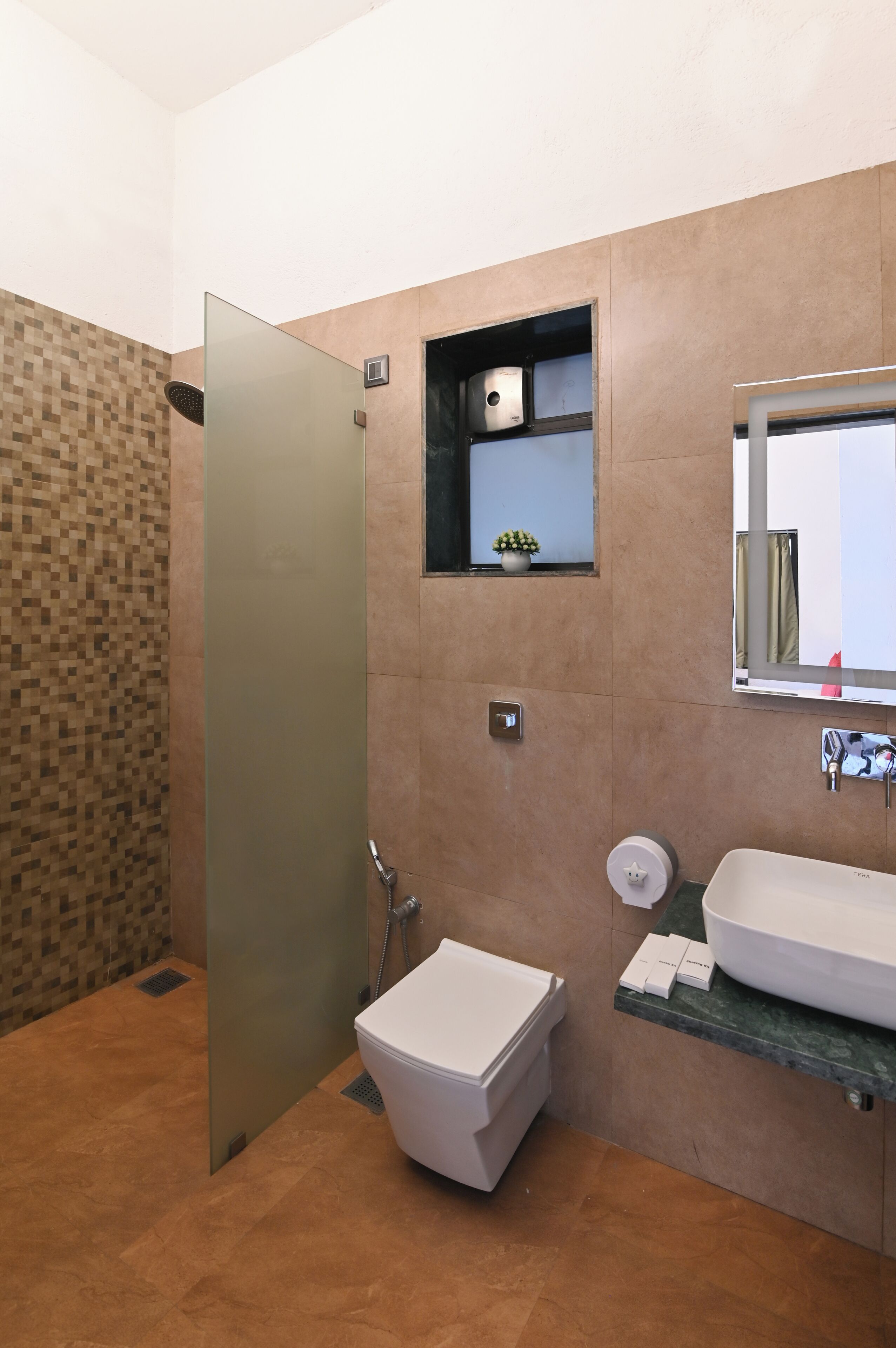 A modern bathroom with a glass shower enclosure, a white toilet, a sink with a marble countertop, and a small shelf with toiletries.
