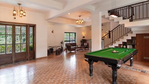 A spacious room with a pool table, wooden furniture, and a staircase leading to an upper level. - Vaarsa By Bay Hotels (Nagaon)
