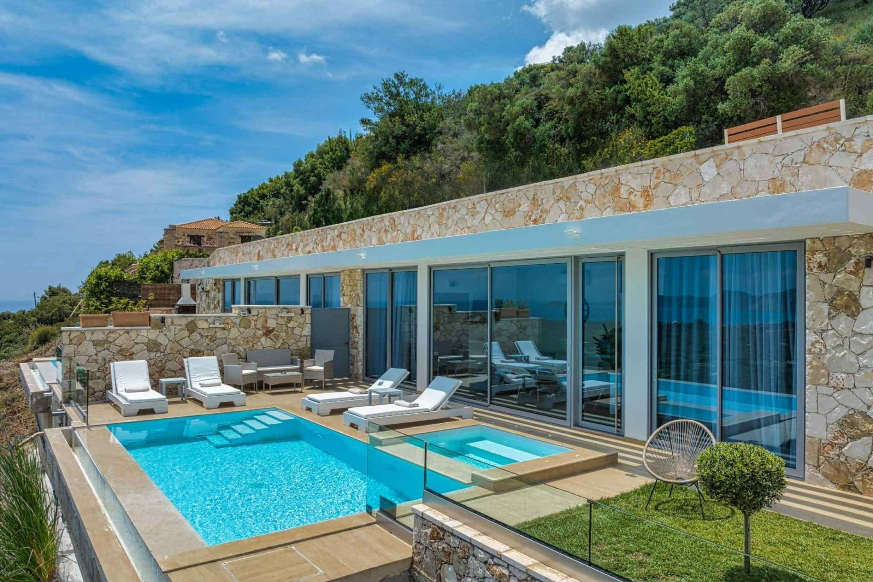 Una villa moderna con piscina, mobiliario exterior y fachada de piedra.