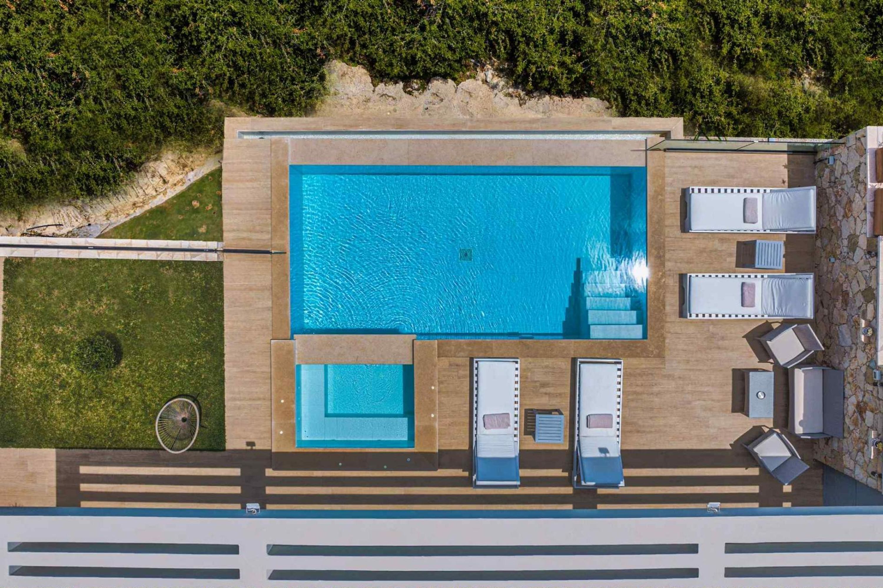 Vue aérienne d’un espace piscine sur le toit, avec une piscine rectangulaire, des chaises longues et un petit coin salon.