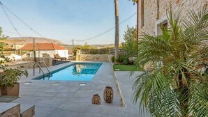 A swimming pool with a stone wall and a palm tree. - Villa Kirke in Chania (Apokoronas)