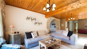 A cozy living room with two sofas, a coffee table, and a stone archway leading to another room. - Villa Kirke in Chania (Apokoronas)