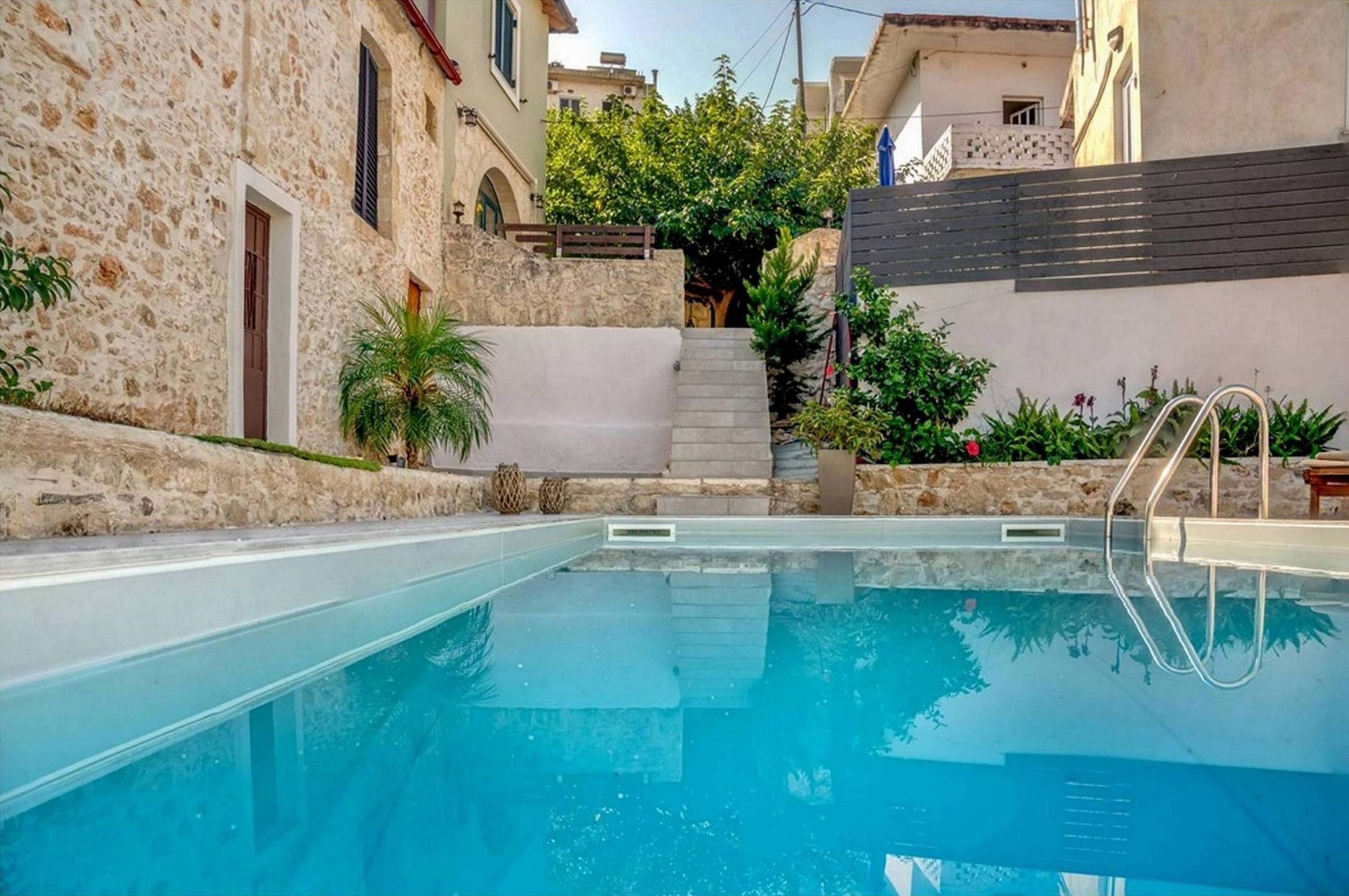 Une piscine aux murs en pierre, avec un escalier et de la verdure.