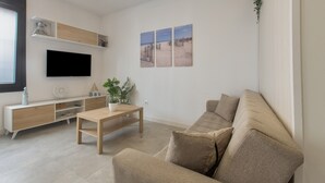Un salon moderne avec un canapé, une table basse, un téléviseur et des œuvres d’art murales.