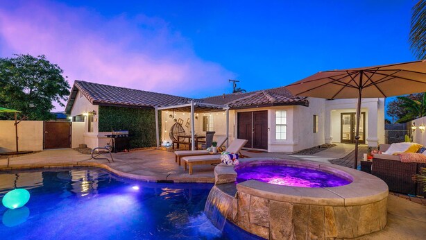 A backyard with a swimming pool, a hot tub, and outdoor seating. - Desert Fun 4BR Retreat | Pool, Jacuzzi & Game Room (Bermuda Dunes)