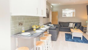 A modern kitchen with a bar area, a dining table set for four, and a living area with a sofa and a coffee table. - Modern Town Centre House w/ En-Suites & Fast WiFi (Tamworth)
