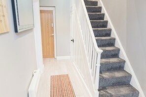 A staircase with a white railing, carpeted steps, and a wooden door at the bottom.