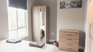 A bedroom with a bed, a wardrobe, a dresser, and a window with a view. - Modern Town Centre House w/ En-Suites & Fast WiFi (Tamworth)