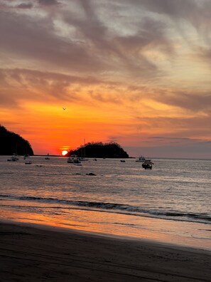 A sunset over a body of water with boats and a distant landmass.