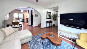 A living room with a sofa, a coffee table, a TV, and a ceiling fan. - Experience a perfect vacation in our newly renovated 3-bedroom townhome in Playas Del Coco (Playas Del Coco)