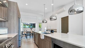 A modern kitchen with a central island, stainless steel appliances, and pendant lighting.