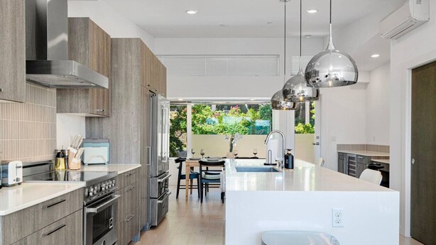 A modern kitchen with a central island, built-in oven, and stainless steel appliances.
