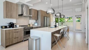 A modern kitchen with wooden cabinets, stainless steel appliances, and pendant lighting.