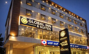 Un hôtel avec une enseigne indiquant « Global Inn & Suites » et une autre indiquant la disponibilité de « chambres de luxe » et d’un « parking ».