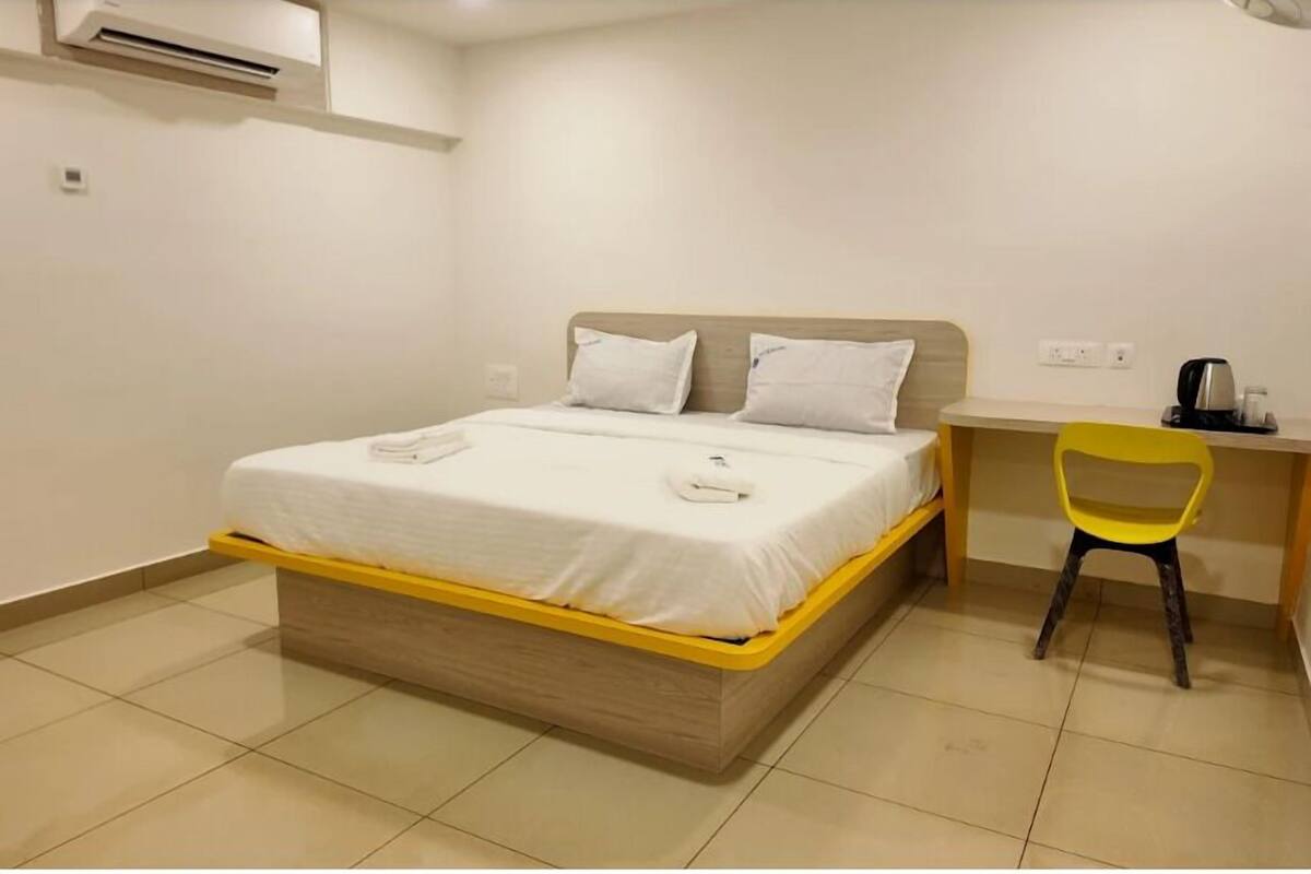 A room with a bed, a desk, a chair, and an air conditioning unit.