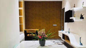 Un espace repas moderne avec une table en marbre, des chaises vertes et un vase de fleurs.