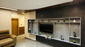 Un salon moderne avec un canapé, un téléviseur à écran plat et des objets décoratifs disposés sur des étagères.