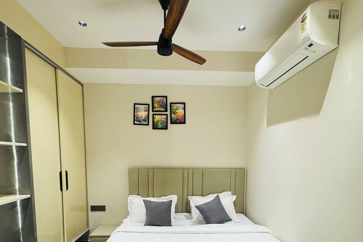 Een netjes ingerichte hotelkamer met een bed, een plafondventilator, een airconditioning en een kledingkast.