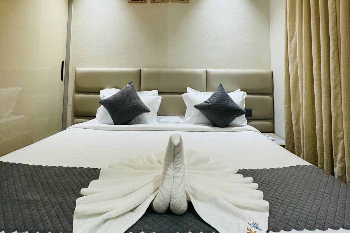 Een hotelkamer met een bed, een plafondventilator, een hoofdbord en een muur met drie ingelijste foto's.