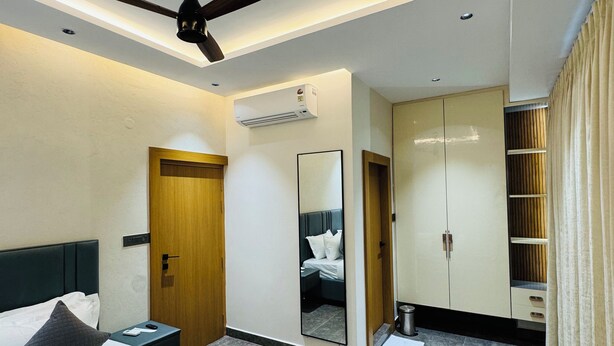 Une chambre d’hôtel moderne équipée d’un lit, d’un ventilateur de plafond, d’une armoire et d’un miroir.